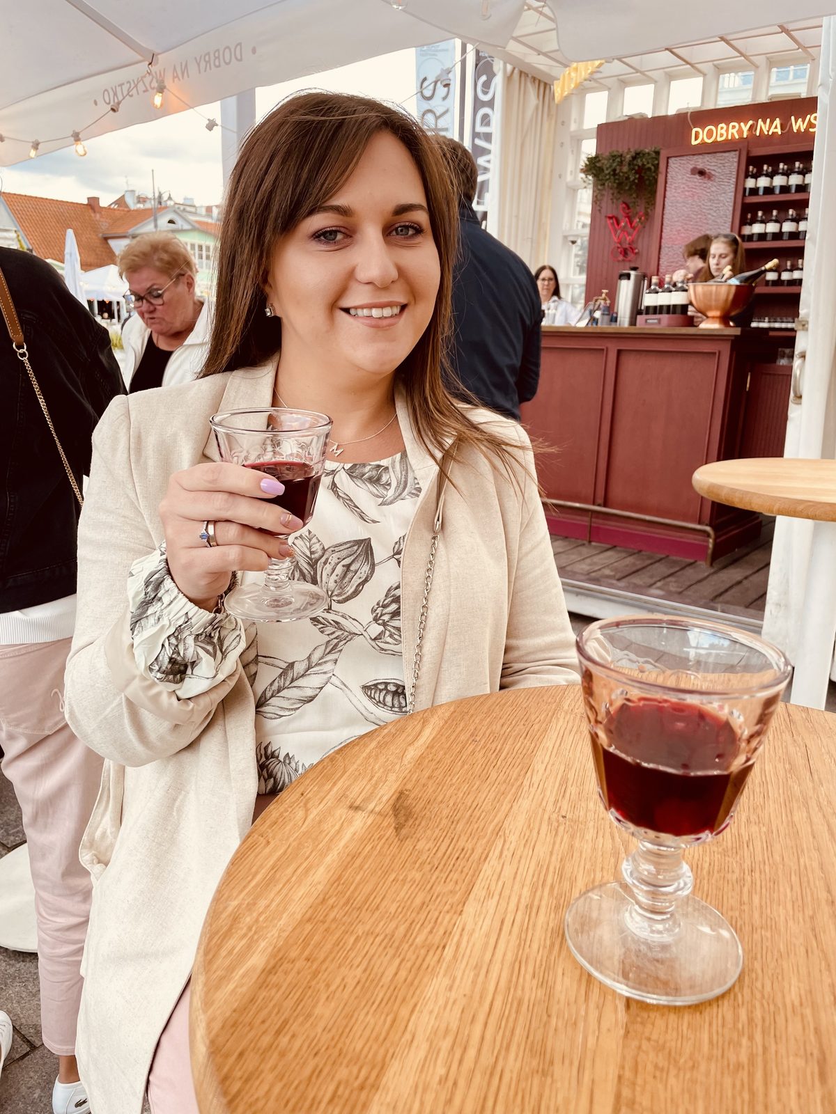 Magdalena at a table outside, glass in hand